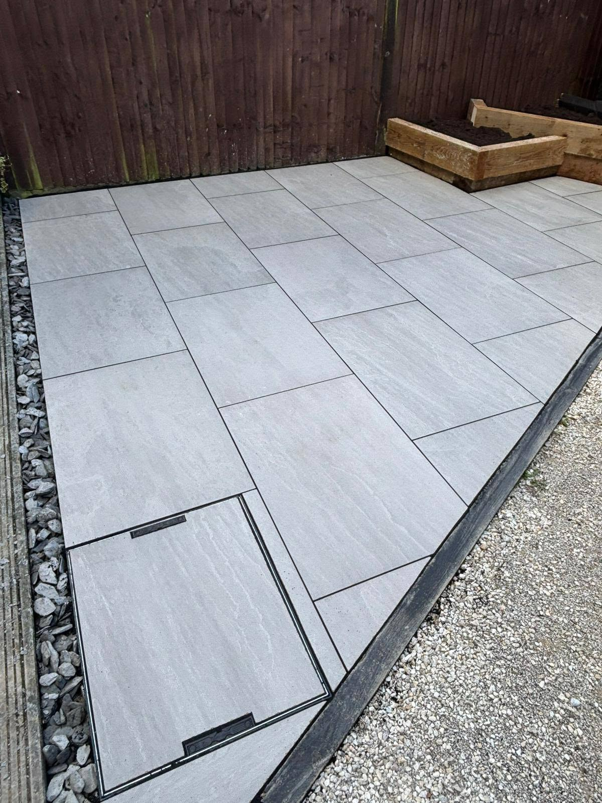 Grey porcelain paving with gravel border and raised timber beds