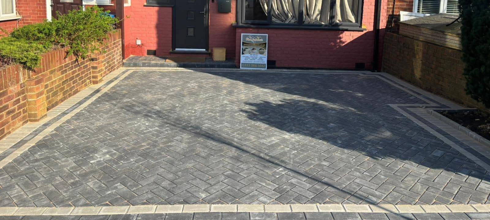 Charcoal herringbone block paved driveway with light kerb border